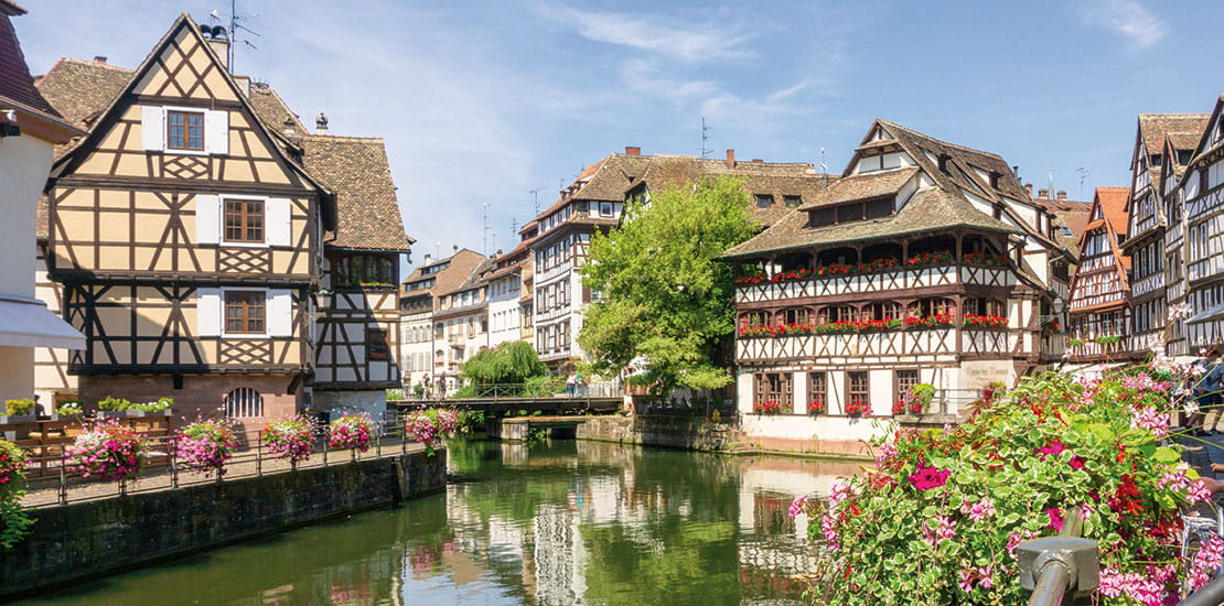 Traditional flower adorned houses lining a canal in the La Petite France area of Strasbourg, France
